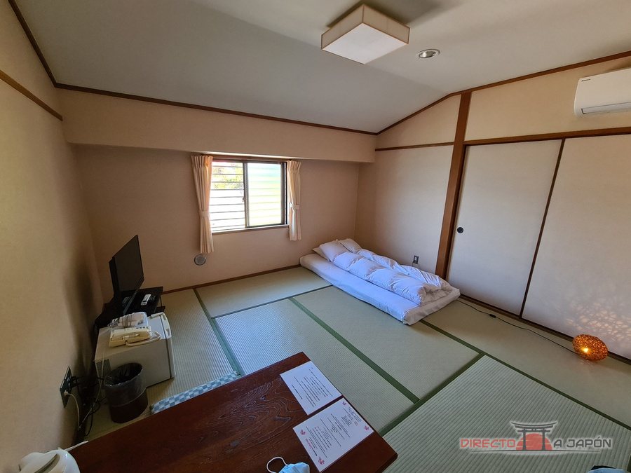 Habitación japonesa del hotel Sakuraya, en Miyajima, con suelo de tatami y un futón preparado junto a la ventana.