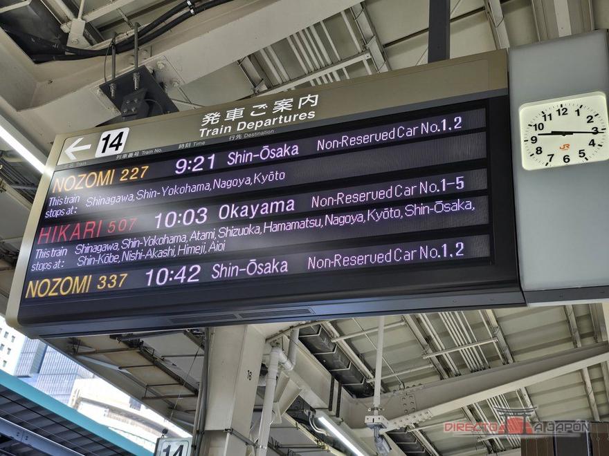 Panel de salidas de un andén de shinkansen con tres trenes: Nozomi, Hikari y Nozomi, con su destino, paradas y coches sin reserva.
