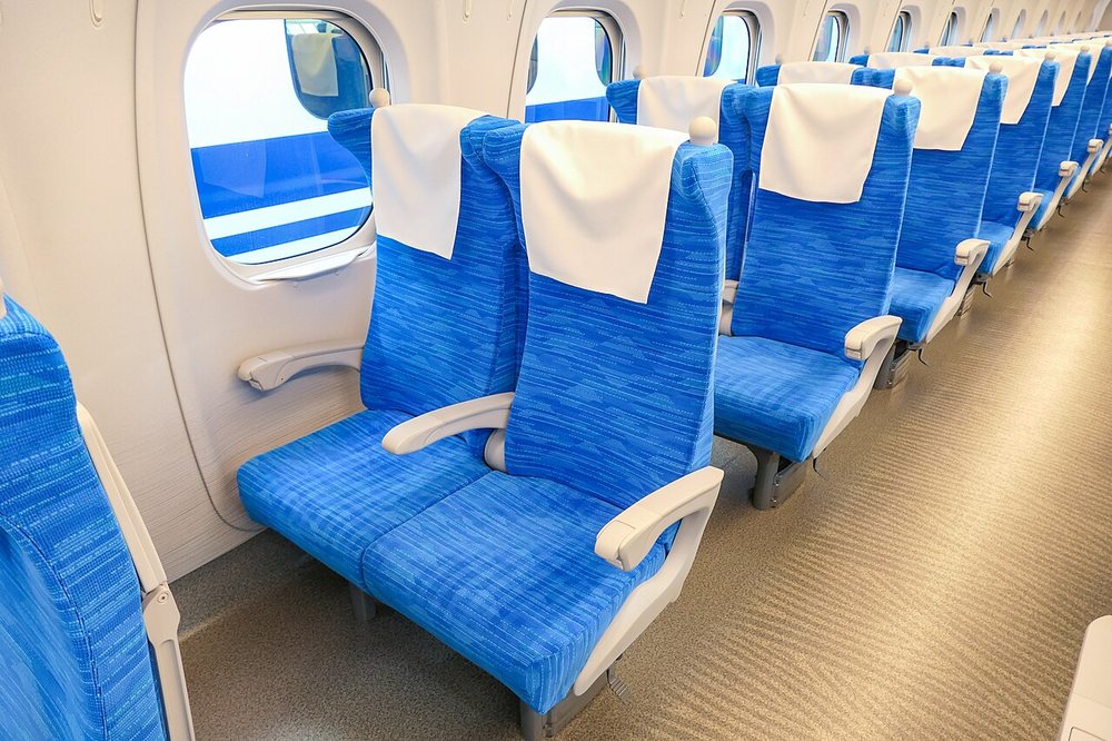 Asientos azules de clase ordinaria de un shinkansen N700S, en filas de dos y tres plazas.