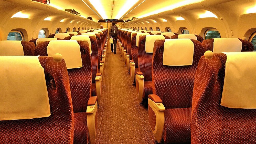Interior de un coche Green de un shinkansen N700S, con filas de asientos reclinables de color granate.
