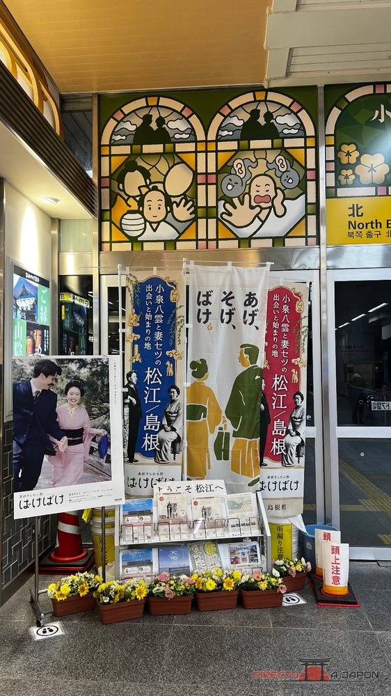 Expositor de Bake Bake en la estación de Matsue con noren, fotografías y vidrieras