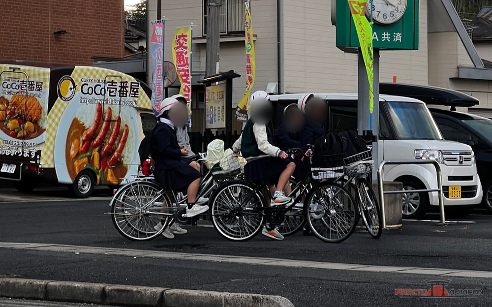 Estudiantes en bicicleta por Matsue y furgoneta de CoCo Ichibanya al fondo