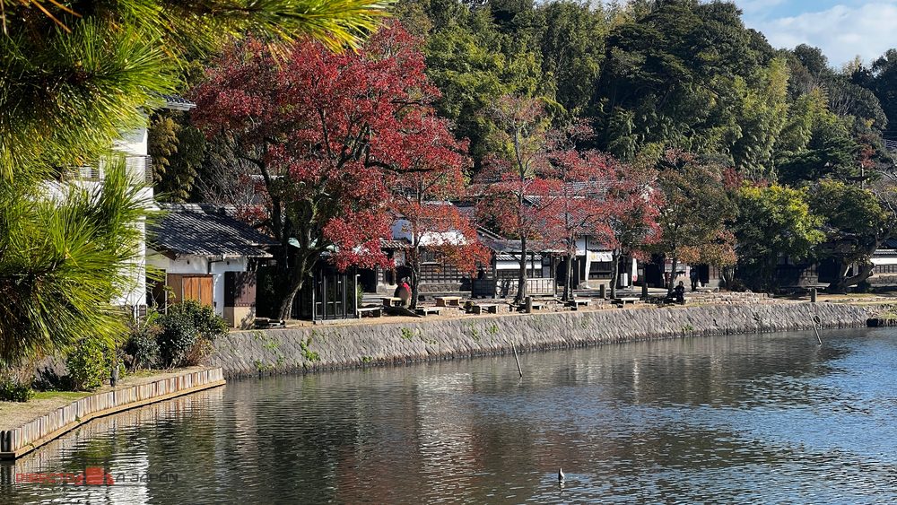 Casas tradicionales y árboles de otoño junto al foso en Shiomi Nawate