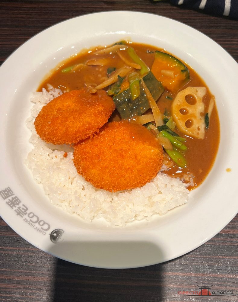Plato de curry con arroz, verduras y dos croquetas cremosas con cangrejo.