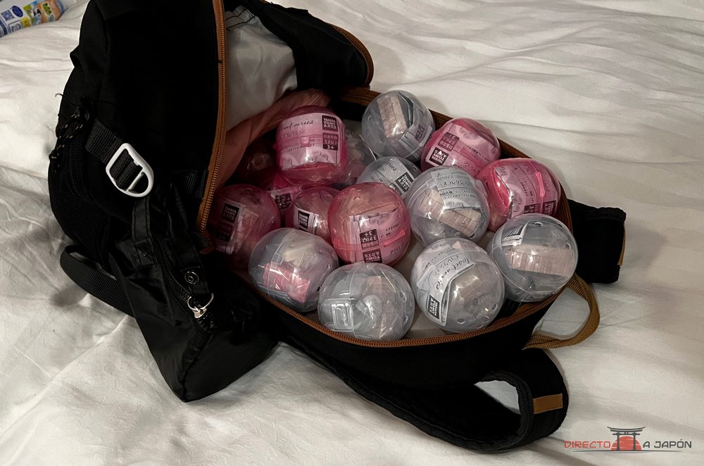 Mochila abierta llena de cápsulas de gachapones rosas y transparentes