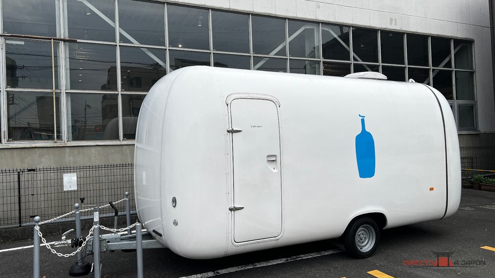 Pequeña caravana blanca con la botella azul