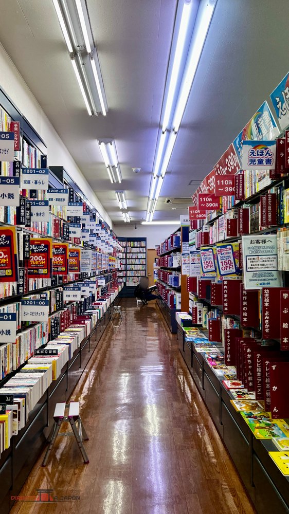 Pasillo con estanterías de libros de segunda mano y carteles en japonés