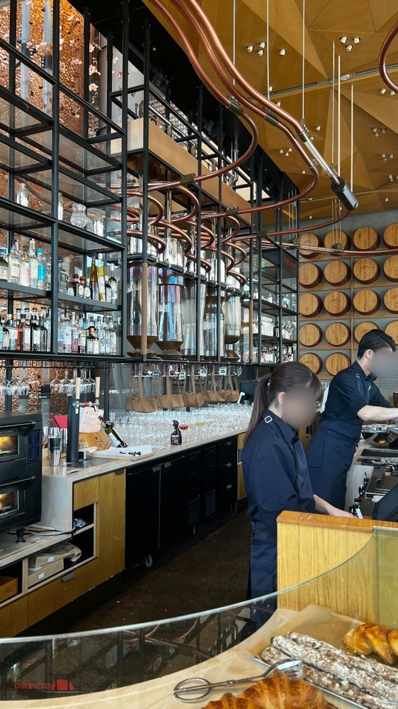 Barra del Roastery con botellas y tuberías de cobre sobre los puestos de trabajo