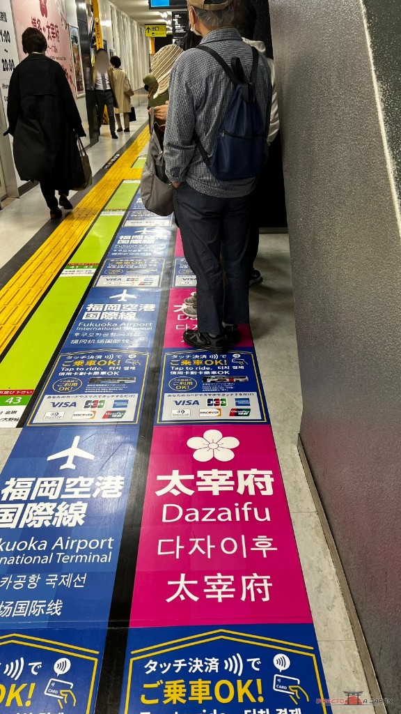 Marcas rosas de la fila para Dazaifu en Hakata Bus Terminal, junto a la fila azul del aeropuerto internacional