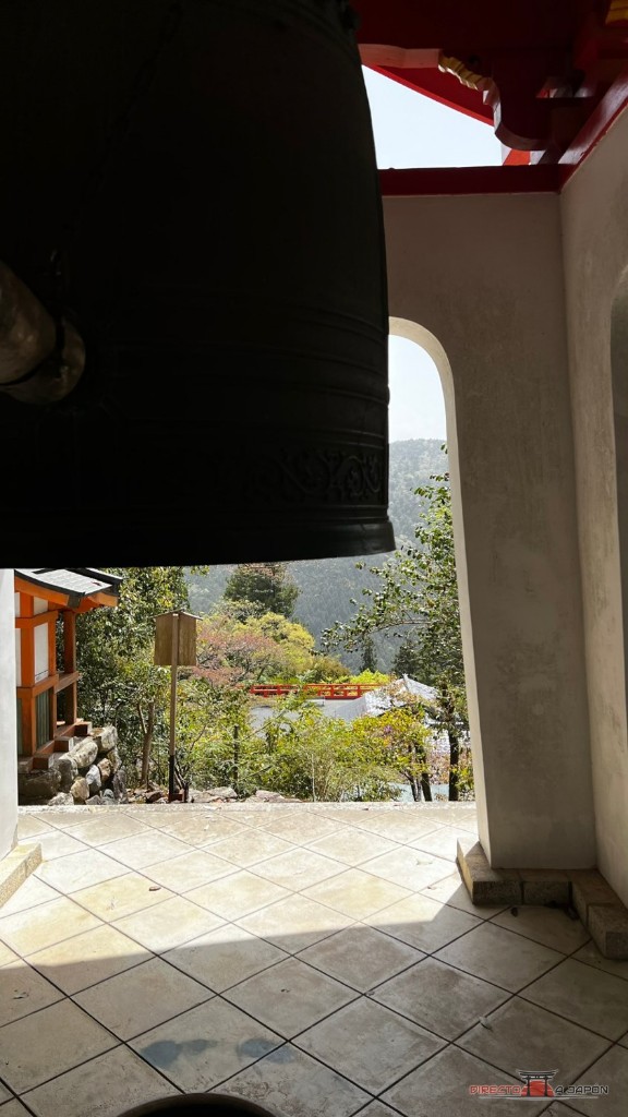 Campana del templo Kurama con el paisaje de montaña al fondo