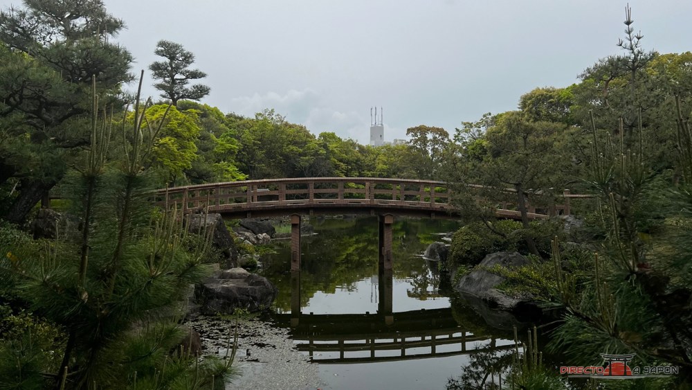 Puente de madera arqueado sobre el agua del Jardín Shirotori