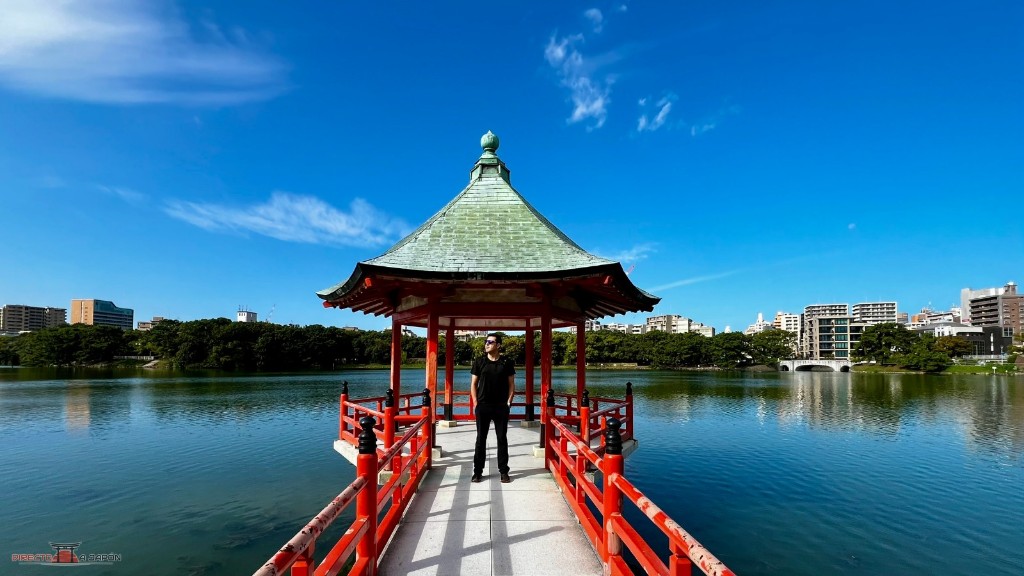 Pabellón rojo Ukimi-do sobre el estanque del parque Ohori de Fukuoka, con la ciudad al fondo