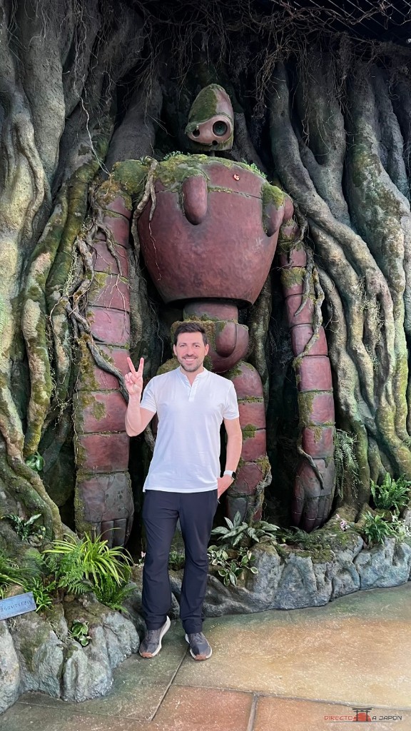 Edu posando junto al robot gigante de Laputa rodeado de raíces en el Grand Warehouse del Parque Ghibli
