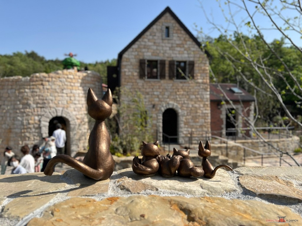 Grupo de figuras de bronce de gatitos junto a una casa de piedra en el valle de las brujas