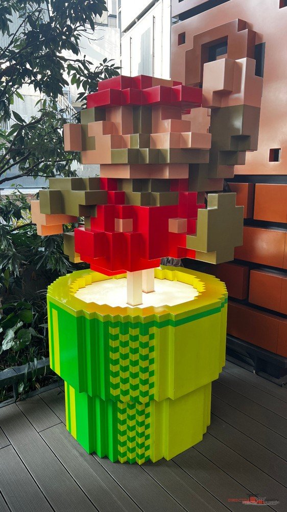Mario pixelado sobre una tubería verde en una tienda Nintendo