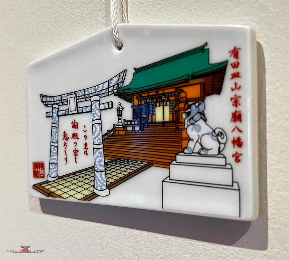 ema de porcelana blanca del Tōzan-jinja de Arita, con un torii decorado en azul y blanco, el santuario de tejado verde y un komainu