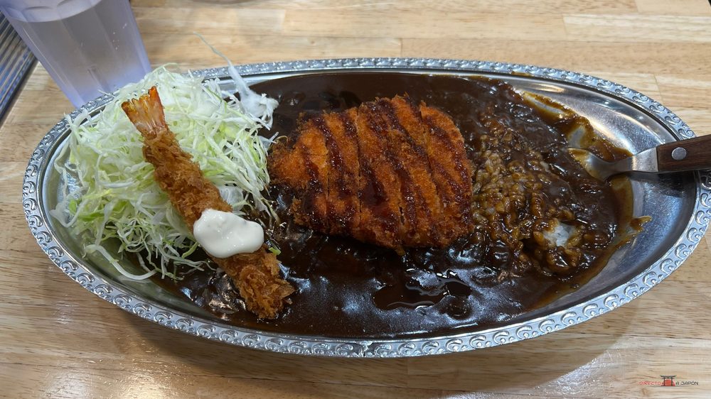 Plato de GoGo Curry en Hakata con katsu, gamba frita, col y salsa en bandeja metálica
