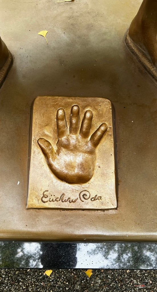 Huella de una mano en bronce con la firma de Eiichiro Oda a los pies de la estatua de Luffy