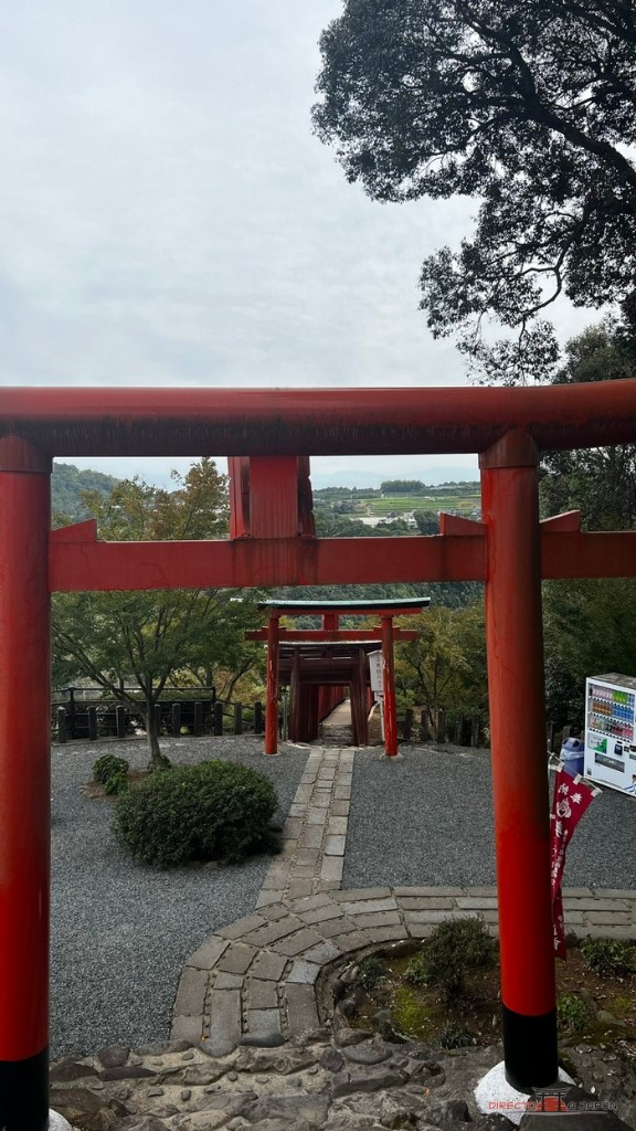 Torii rojo grande que enmarca el valle y otro torii más pequeño al fondo, en un jardín de piedras