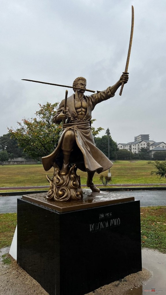 Estatua de Zoro en pose de ataque con espada en alto sobre un pedestal negro en el parque de Ōzu